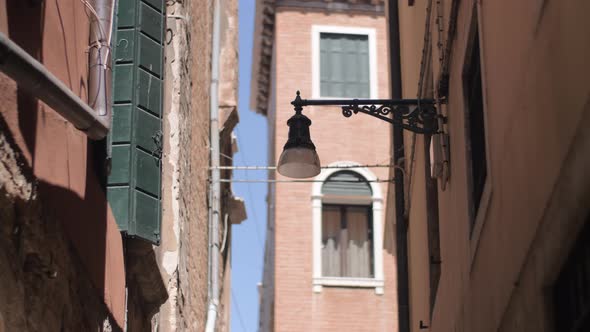 A wall mounted streetlight on a narrow Venice street