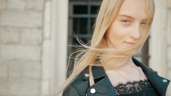 fashion portrait of a beautiful young woman with blue eyes and blonde hair in a leather jacket outdo