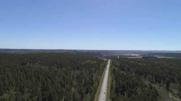 Aerial view of cars go on the highway, the highway goes through the forest 03