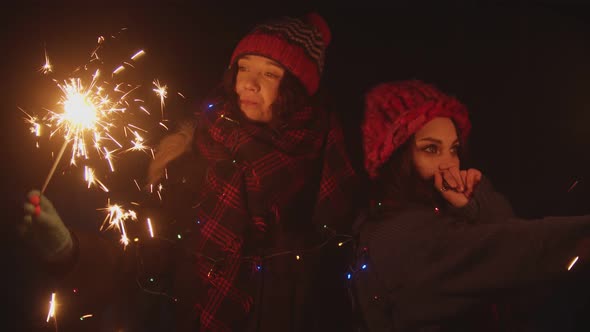 Two Young Women Friends Playing with Sparklers at Night and Dancing