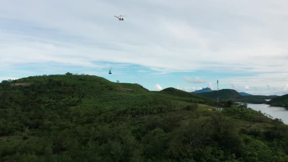 Helicopter carrying cargo to telecommunication tower on remote tropical island