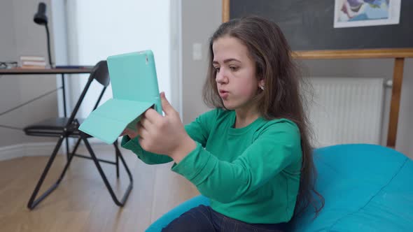 Medium Shot Portrait Positive Charming Little Person Sitting on Bag Chair Talking at Tablet Video