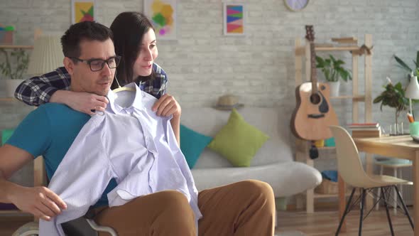 Close Up Young Woman Helps a Disabled Person in a Wheelchair To Get Dressed