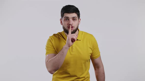 Man with Beard Holding Finger on Lips Over White Background