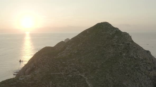 Rocky peak then a glimpse of modern buildings on a craggy mountain