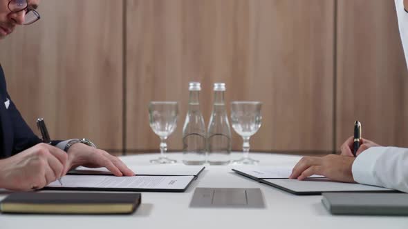 Businessman Sign Contract Documents with a Arab Partner While Sitting at the Table a Handshake