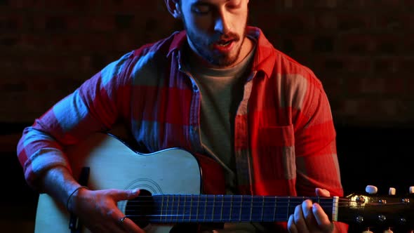 Handsome musician singing song while playing guitar