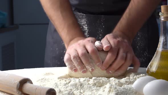 Male Hands Kneading Dough with Flour on Kitchen Table