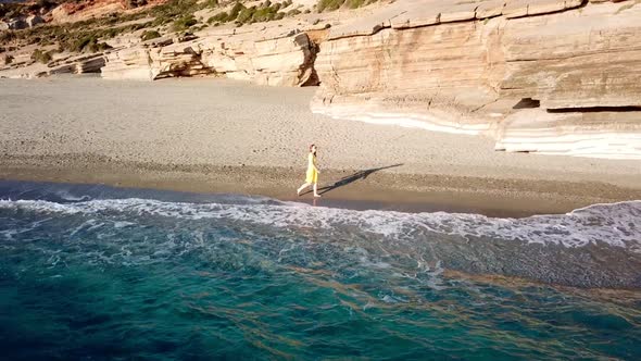 Aerial Drone Footage of a Girl Walking Along a Lonely Beach