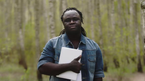 Portrait of Young African Man Holding Tablet in the Park