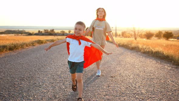 Two Running Children in Field Under Sunlight Brother and Sister Put Homemade Superheroes Costumes