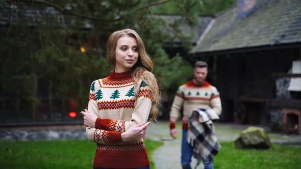 Lovely girl and a guy outdoors. Man covering his girlfriend's shoulders with a blanket in autumn