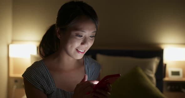 Woman use of smart phone on bed at night