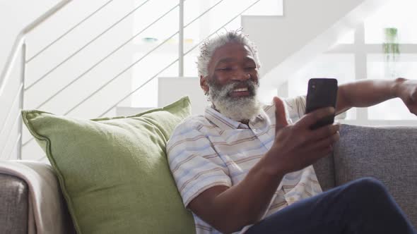 Senior man having a video chat on his smartphone at home
