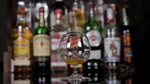 Closeup of the Bartender Pouring Cognac Into a Glass in the Bar