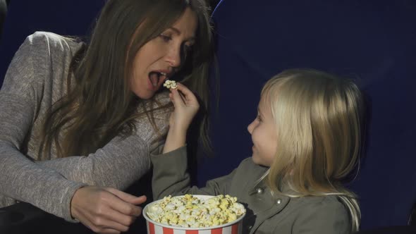 Adorable Little Girl Feeding Her Mom with Popcorn at the Cinema
