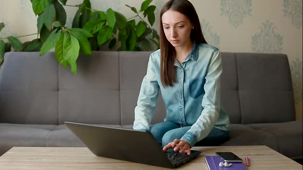 Long Haired Lady Sits at Wooden Table with Black Laptop