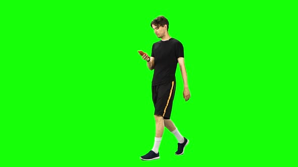 Brunette Man Goes and Texting with Smartphone on Green Screen at Studio.. Slow Motion
