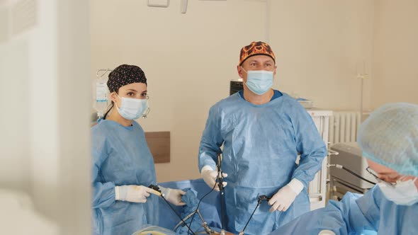 Surgeons Team Looks at Monitors While Preforming Operation in Hospital Operating