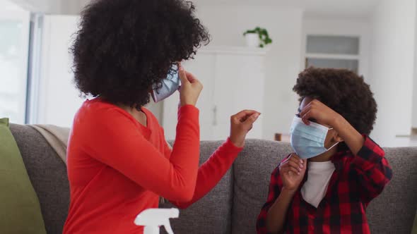 Mother putting face mask on her son at home