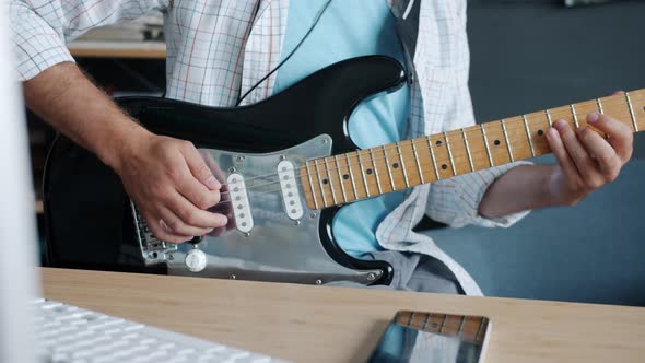 Closeup Slow Motion of Guitarist's Hands Playing Electric Instrument Indoors in Studio