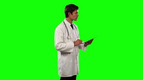 Side view of a doctor using his digital tablet with green screen