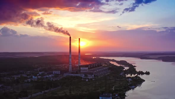 Beautiful sunset with power plant on front view. Red and yellow sky above river. Video from drone.