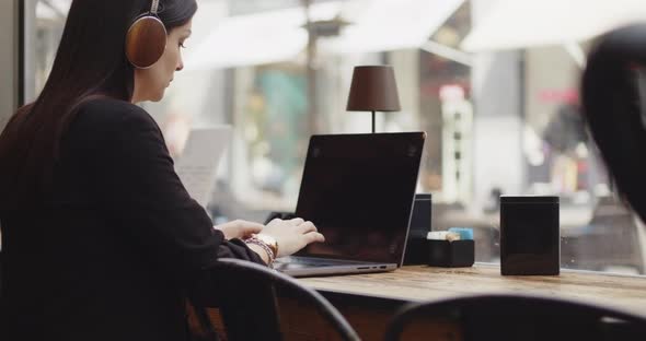 Back View of Caucasian Woman Working on a New Project in a Coffee Shop