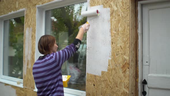 Beatiful Woman Paints the Wooden Wall of Her Own Wooden House