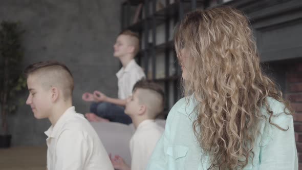 Portrait Pretty Mother Sitting in the Living Room with Her Three Teen Sons Meditating Together