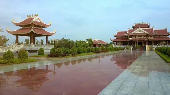 Drone Moves Up Above Temple with Red Pagodas and Clear Pool