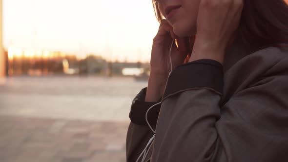 Young attractive business woman sitting outdoor on the bench and using smartphone.