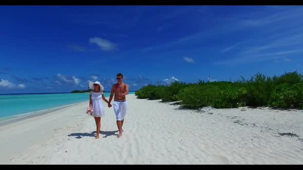 Man and woman posing on paradise coast beach vacation by turquoise water with bright sandy backgroun