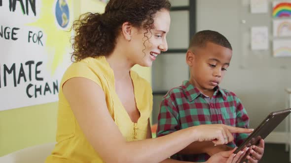 Video of happy caucasian female teacher and african american boy studying ecology in classroom alt