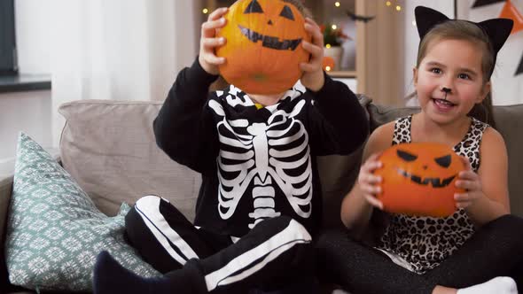 Kids in Halloween Costumes with Pumpkins at Home