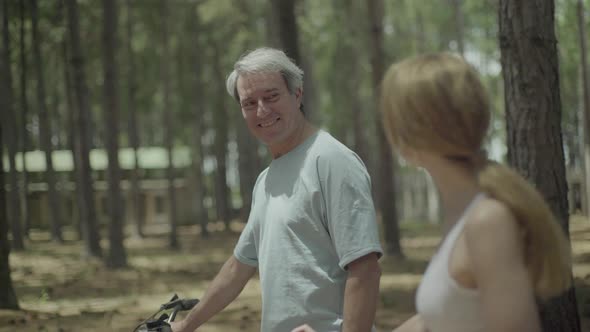 Mature couple walking bicycles in woods