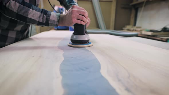 Carpenter Sanding Wood and Resin Countertops in Workshop