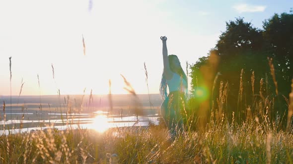 Woman with Long Braids Slowly Dancing on Sunset Wheat Field