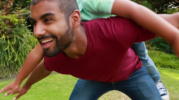 Father giving son piggyback ride in garden 4k