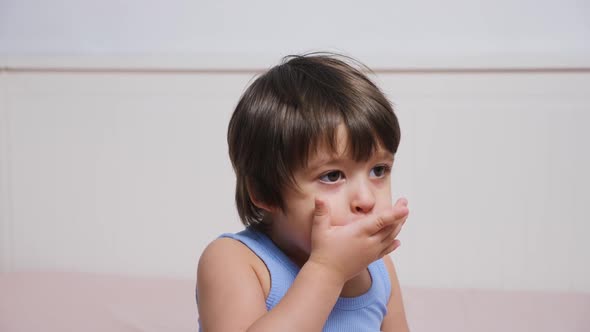 Little Boy Covers His Mouth with His Hand