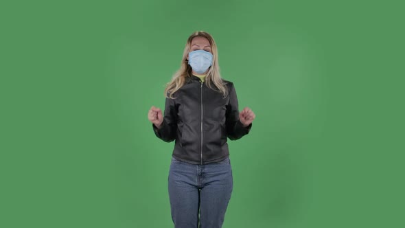 Portrait of Beautiful Young Woman in Medical Mask Is Looking at Camera and Pointing Up Fingers