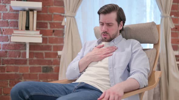 Young Man Coughing While Sitting on Sofa