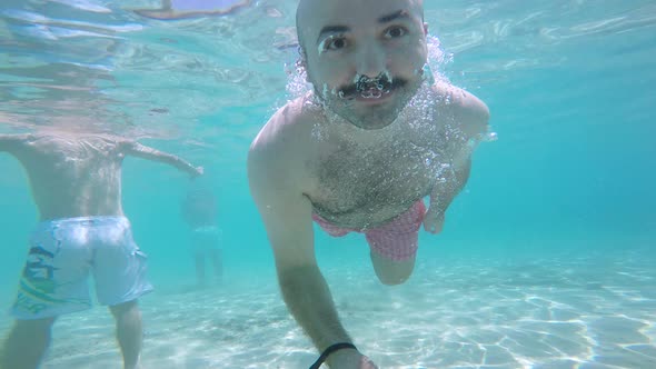 bald man diving into the sea with camera in hand on summer vacation.