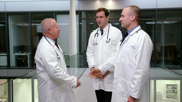 Doctors interacting with each other while shaking hands in corridor