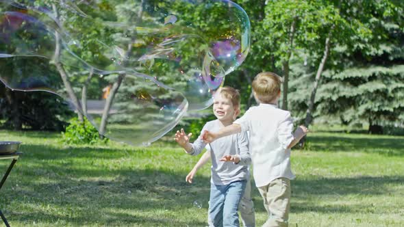 Adorable Little Boys Bursting Giant Soap Bubble during Performance