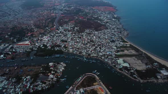 Aerial drone view of overpopulated coastal Phan Thiet Vietnamese city at dusk.