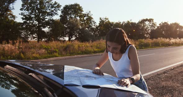 Alone Woman Driver Studying Map on Car Hood, Planning Her Route at Countryside