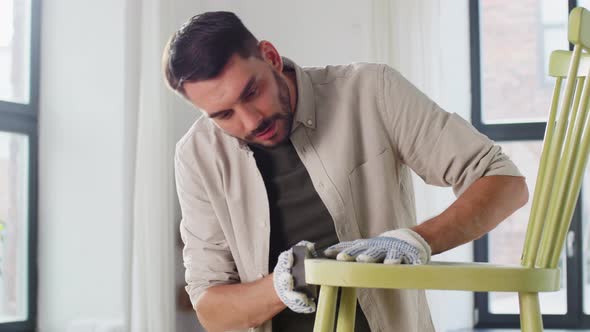 Man with Sponge Sanding Old Wooden Chair at Home