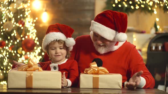 Santa Claus and Child with Christmas Gift Boxes at Home.