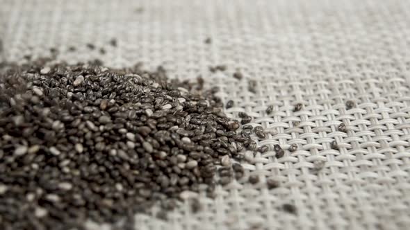 Chia seeds fall onto a woven plastic textured surface